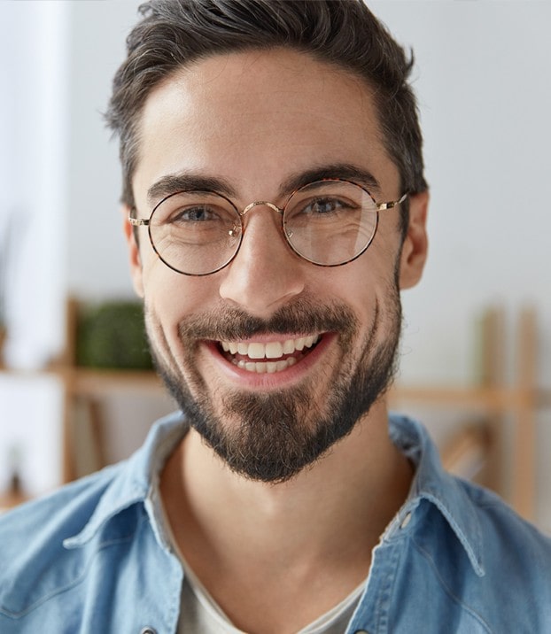 A man is smiling while wearing his new glasses from OPMT Vision Centers.